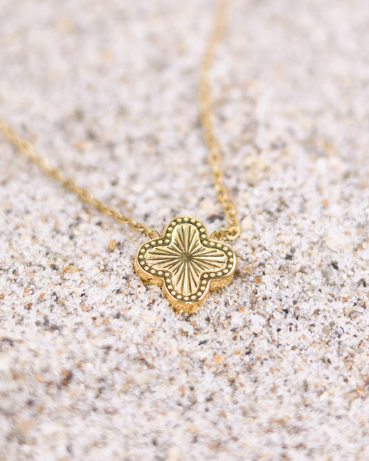 Sunburst clover pendant necklace worn on white eyelet blouse