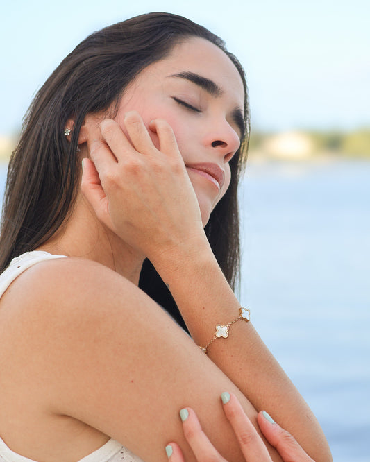 Feminine golden bracelet with delicate white enamel floral charms