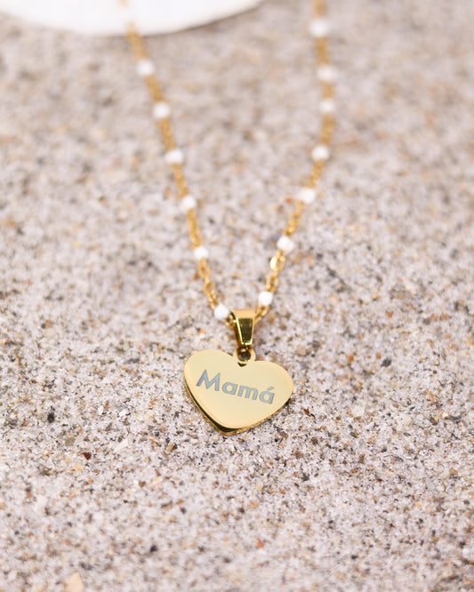 Personalized engraved heart pendant with white bead chain worn by woman on neutral-toned outfit
