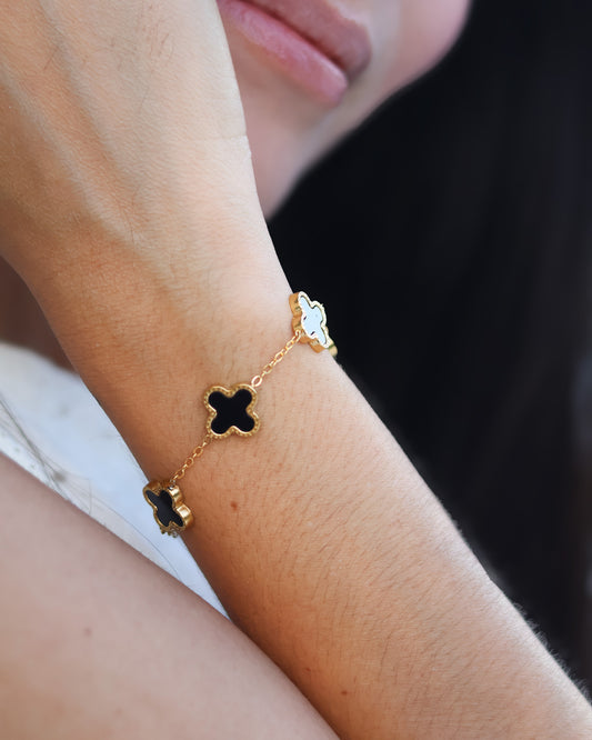 Dainty bracelet with black clovers outlined in gold, bold and elegant