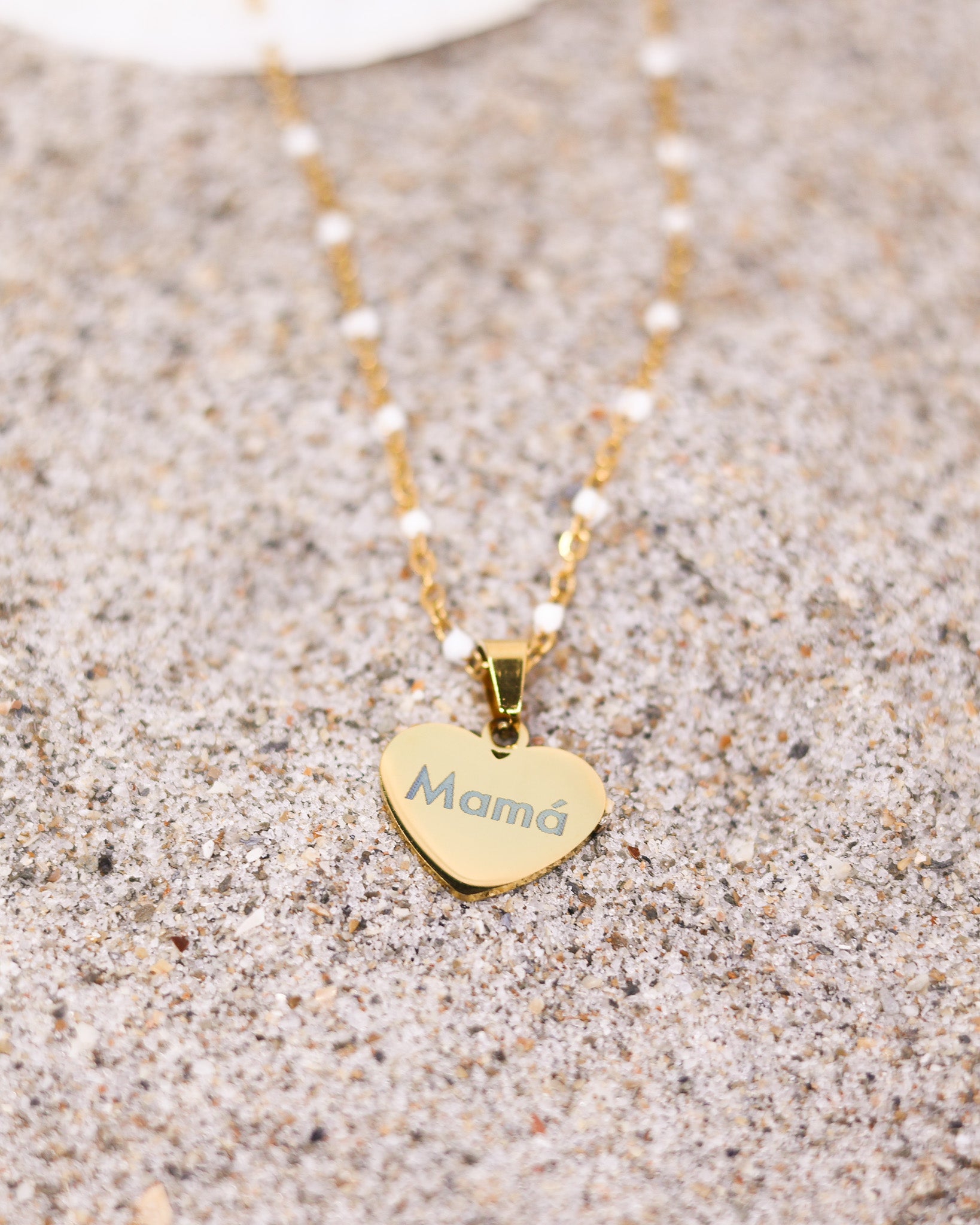 Personalized engraved heart pendant with white bead chain worn by woman on neutral-toned outfit