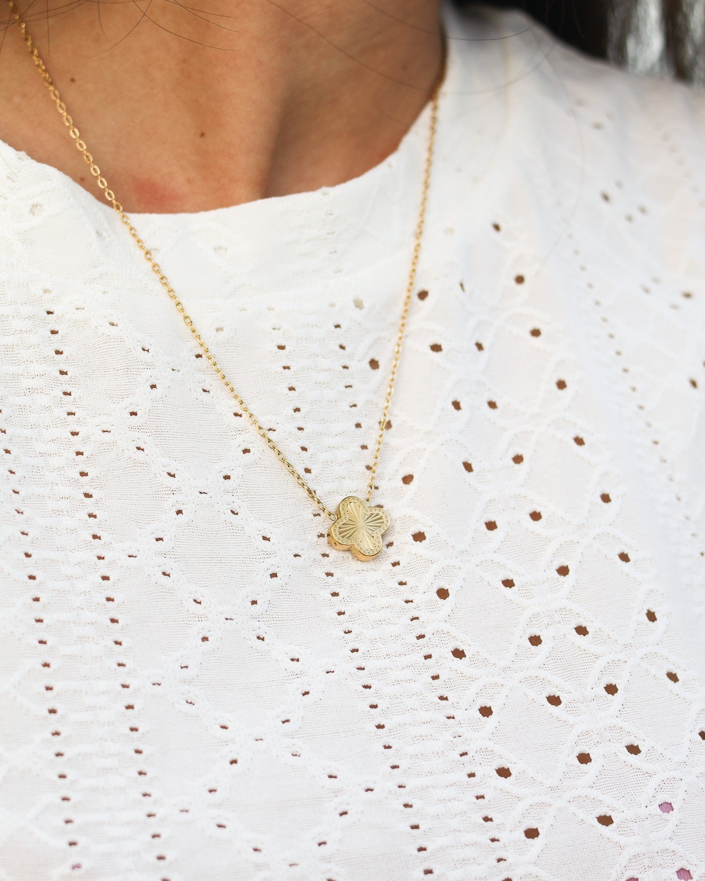 Woman gently holding clover necklace, eyes closed in serene beach moment