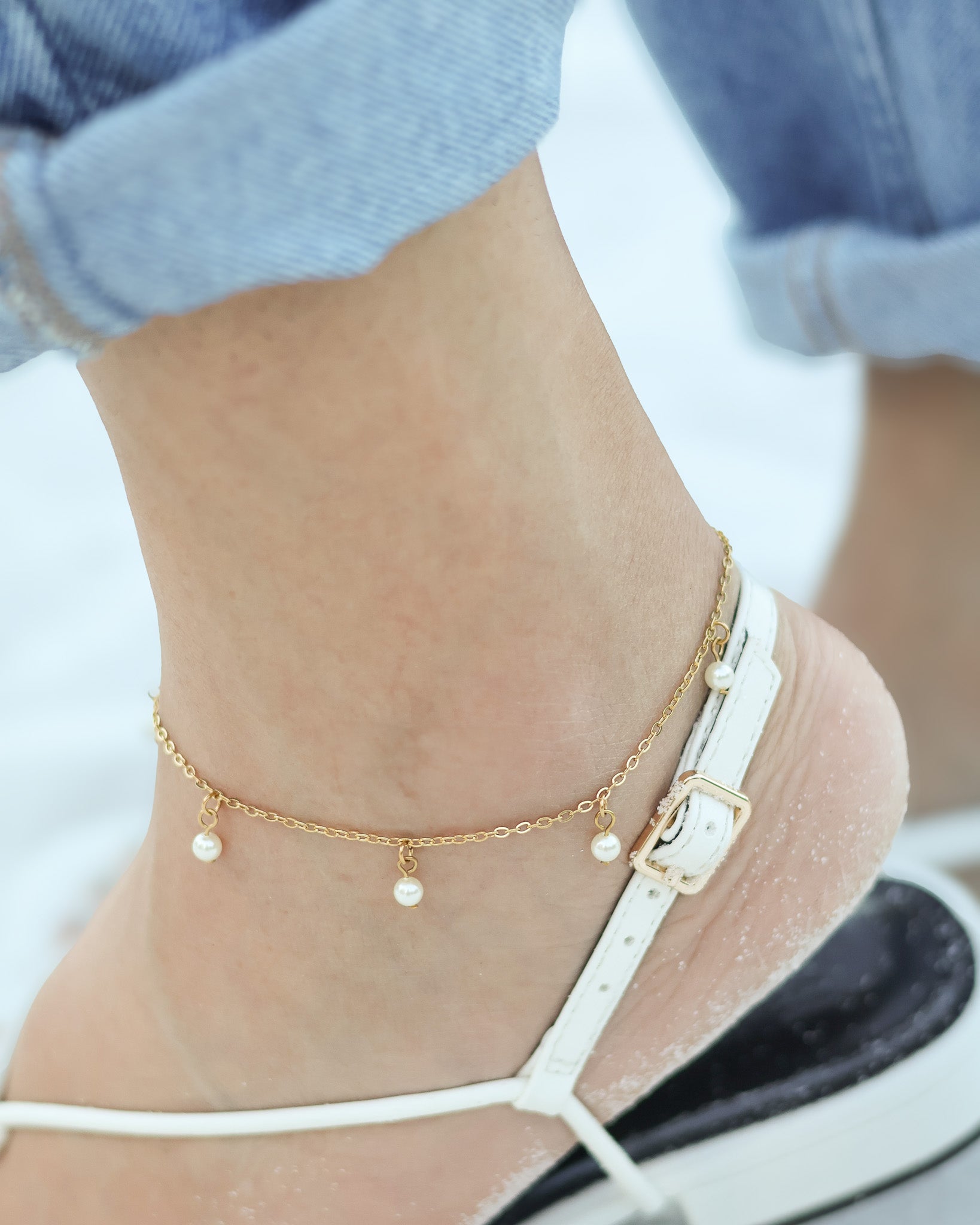 Dainty waterproof pearl anklet shimmering in natural sunlight, designed for barefoot beach days