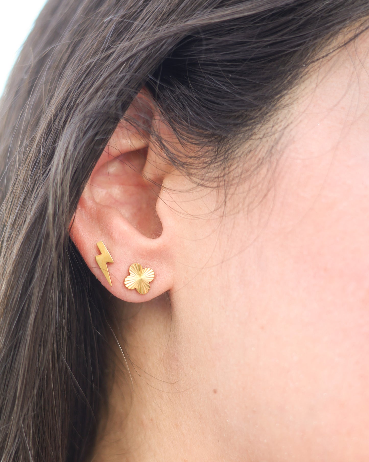Model wearing gold clover stud earrings with casual summer outfit and soft coastal styling