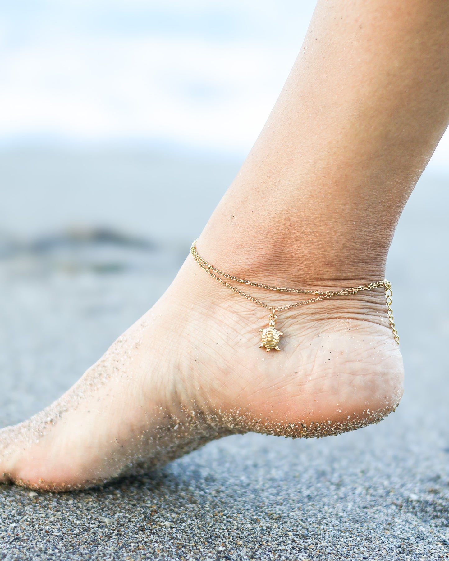 Elegant beach-style anklet with turtle charm, white beads, and gold polished finish