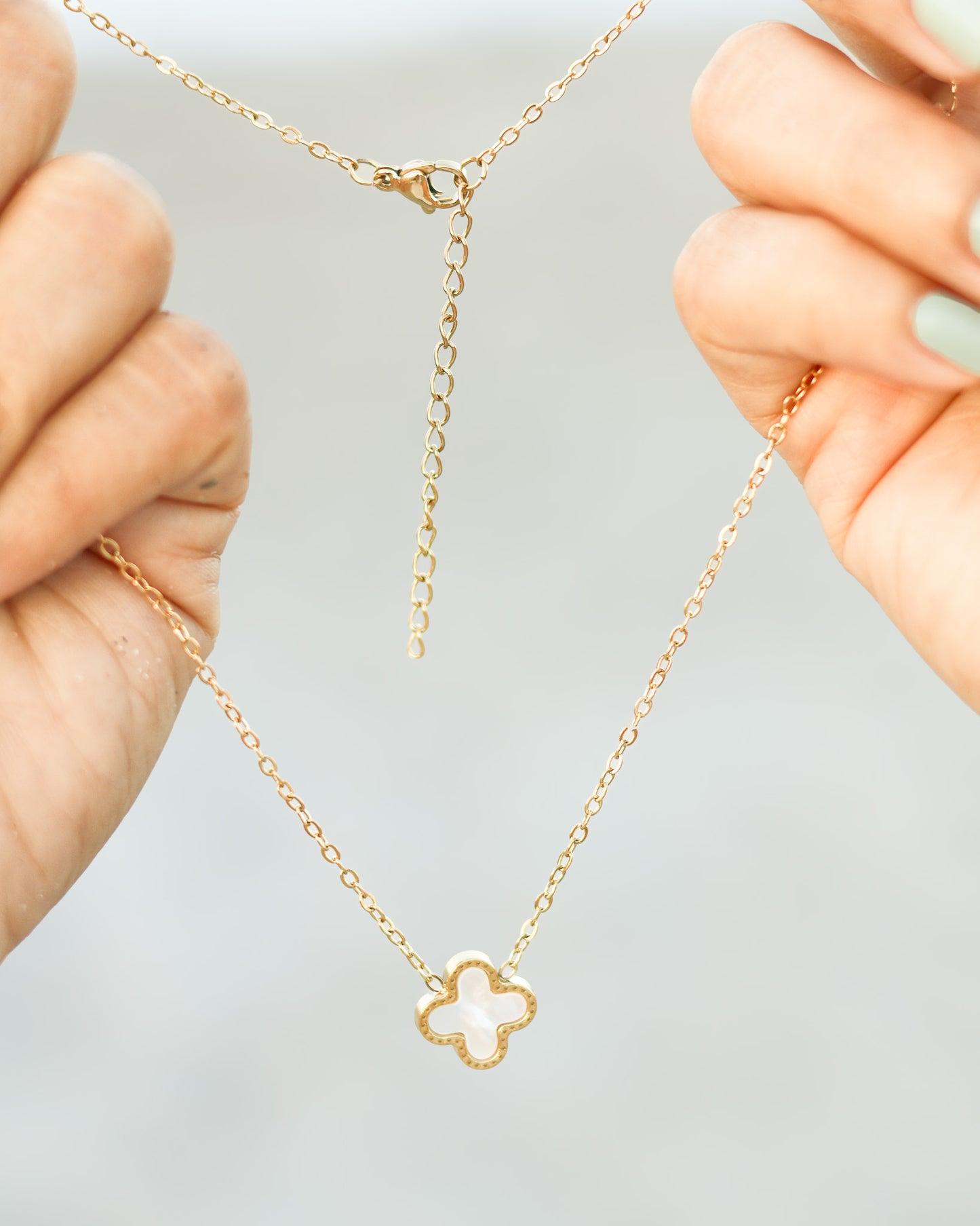 Four-leaf white clover charm necklace layered in dainty gold