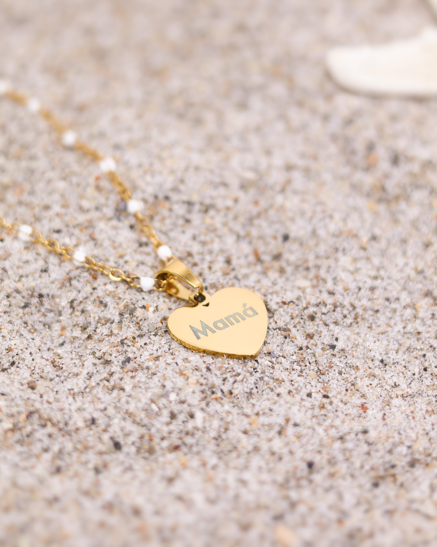 Minimalist engraved gold heart necklace showcased in warm coastal light on skin