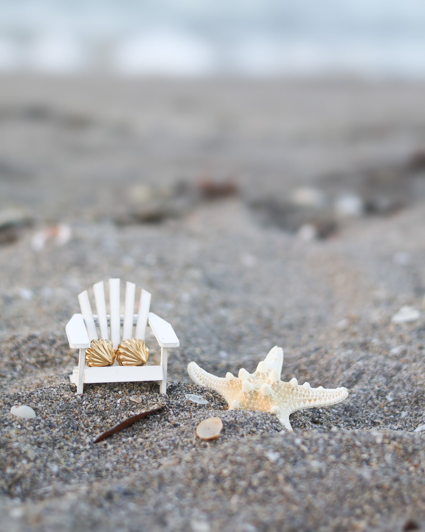 Golden seashell earrings styled on mini beach chair with starfish