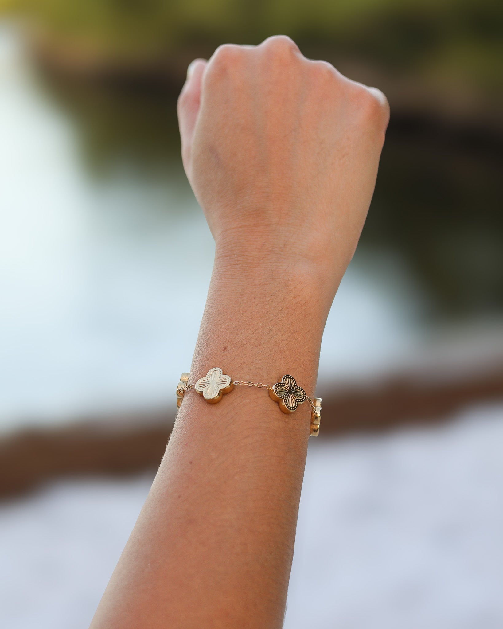 Woman wearing gold clover bracelet styled with summer dress