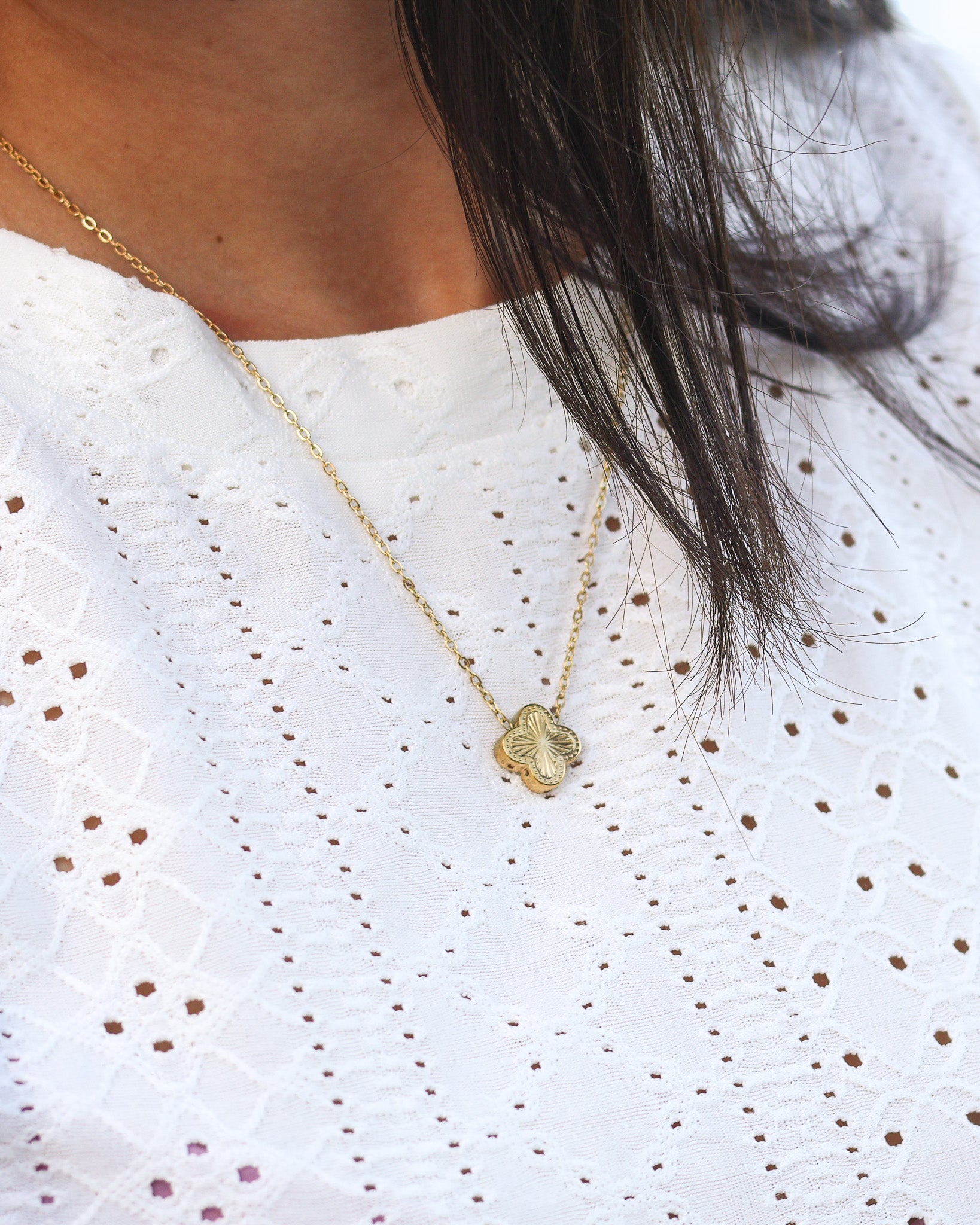 Gold four-leaf clover necklace styled with feminine white top